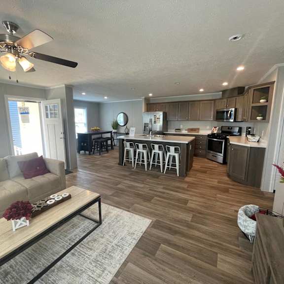 a living room with a couch, coffee table, and a kitchen in the background.