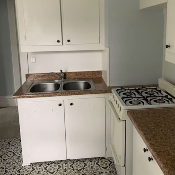 a kitchen with white cabinets and a brown counter top.