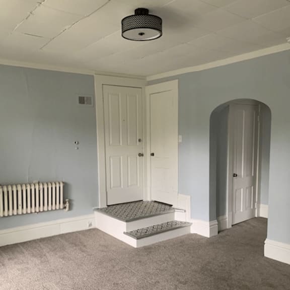 a room with a white door and a grey carpet.
