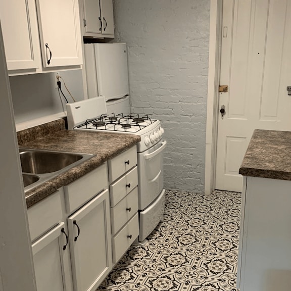 a kitchen with white cabinets and a black and white floor.