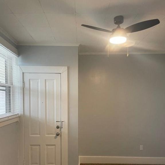 a room with a ceiling fan and a door.