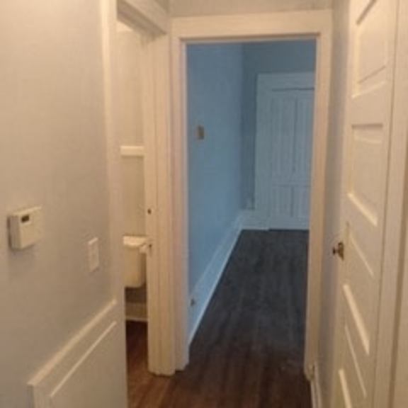 a hallway with a white door and a white wall.