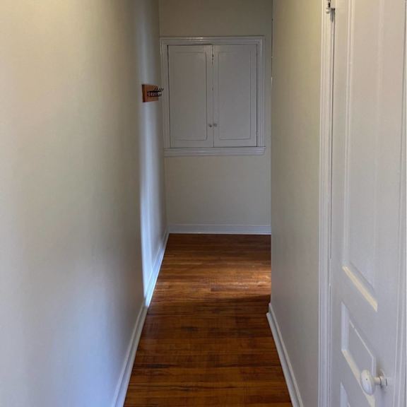 a hallway with a white door and a red sign on the wall.