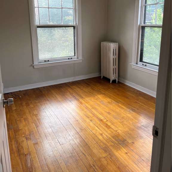 a room with wooden floors and two windows.