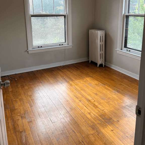a room with wooden floors and two windows.