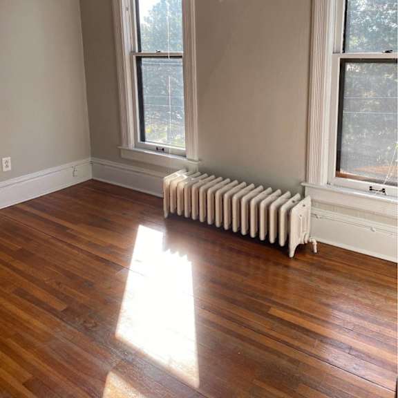 a room with a white radiator and wooden floors.