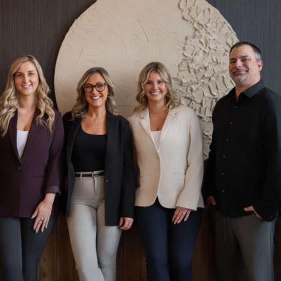 five people are standing in front of a decorative wall.