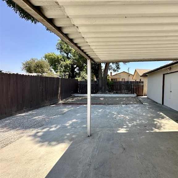 a concrete patio with a white pole and a white wall.