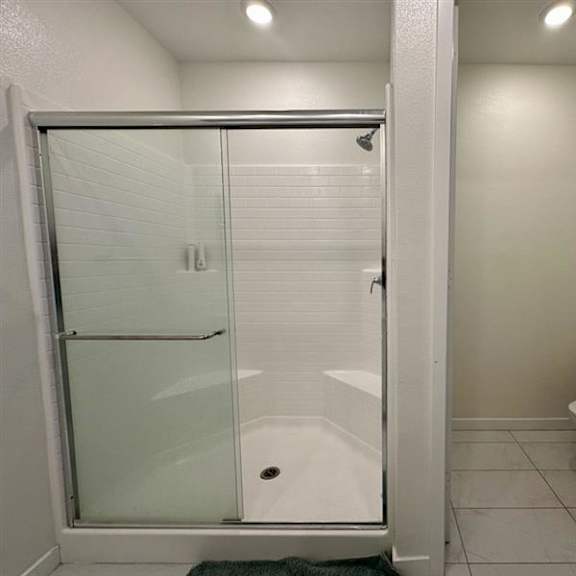 a white bathroom with a glass shower door and a toilet.
