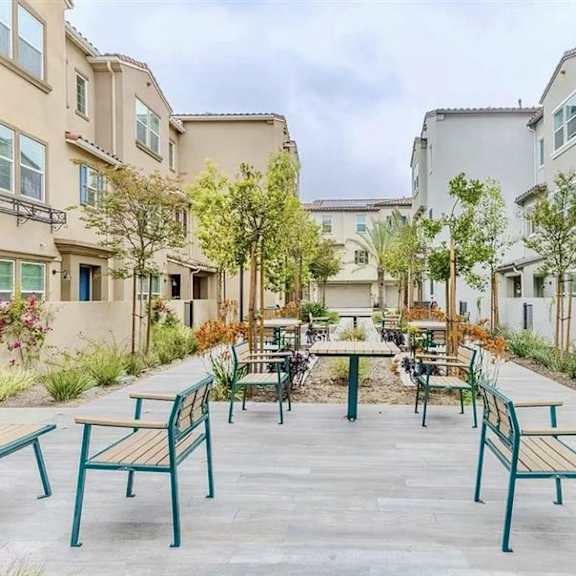 a patio with benches and trees in front of apartment buildings.