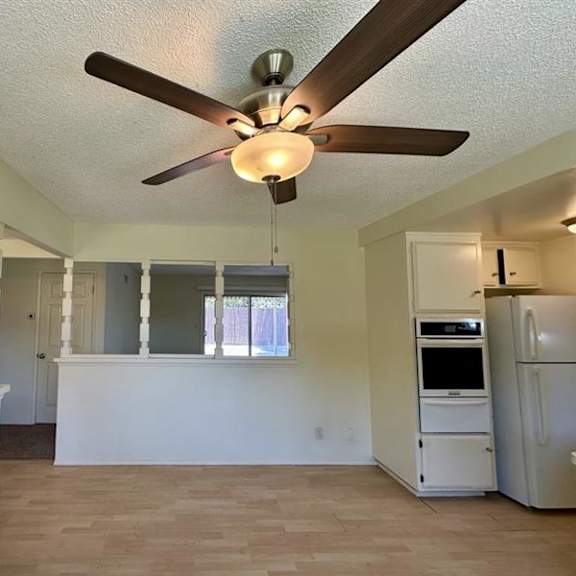 a room with a ceiling fan and a refrigerator.