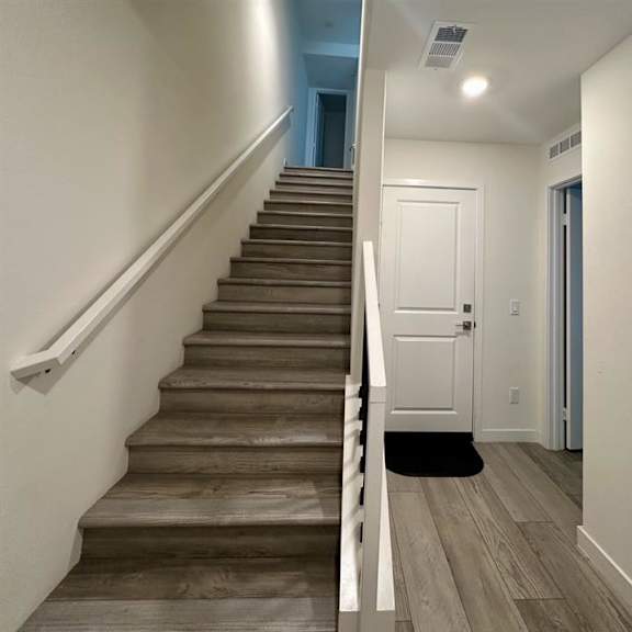 a staircase with a white railing and wooden steps leading to a door.