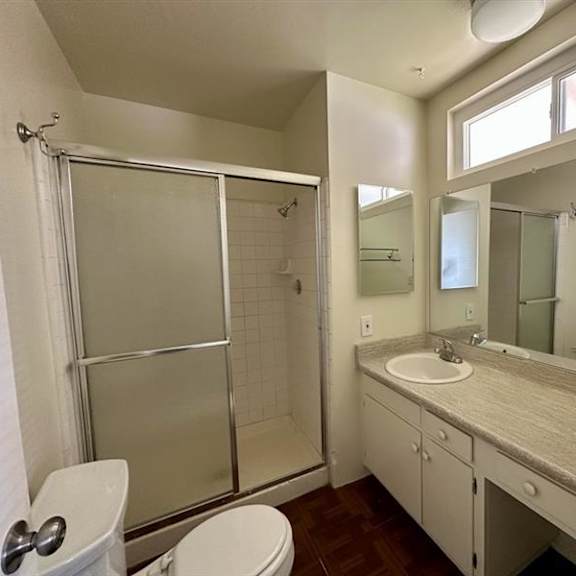 a bathroom with a toilet, sink, and shower.
