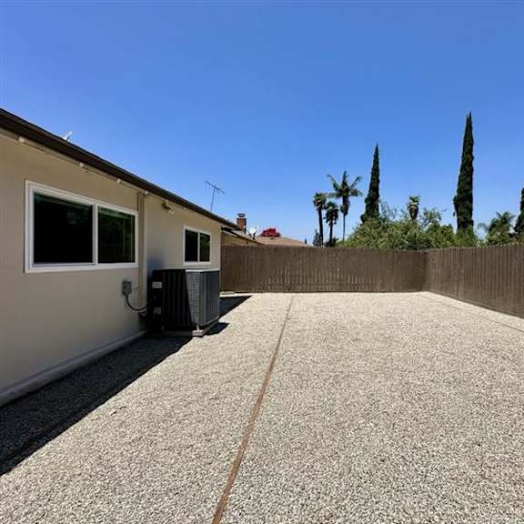 a backyard with a concrete floor and a wooden fence.