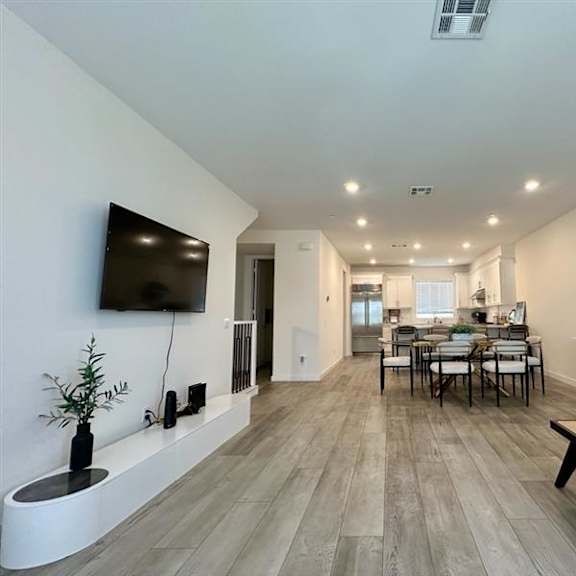 a modern living room with a long wooden floor and a flat screen tv mounted on the wall.