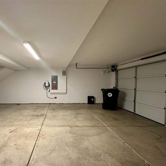 a large, empty garage with a black trash can and a red fire extinguisher mounted on the wall.