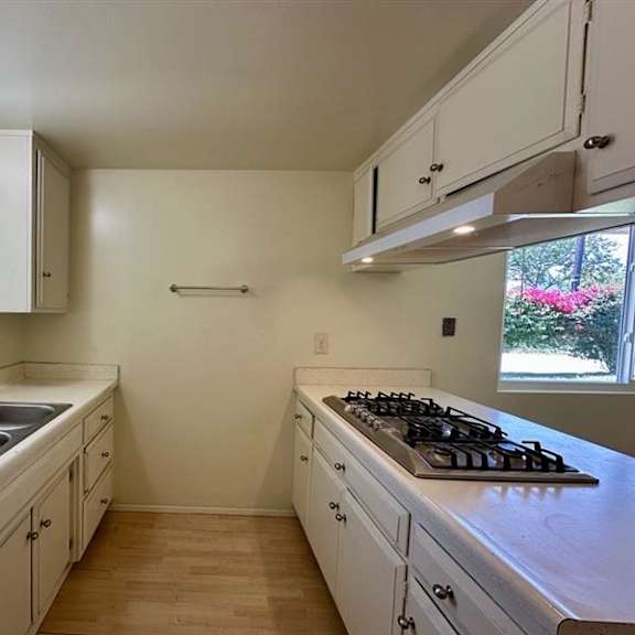 a kitchen with white cabinets and a wooden floor.