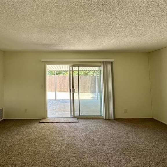 a room with a carpeted floor and a sliding glass door leading outside.