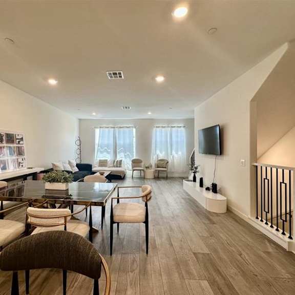 a spacious living room with a dining table and chairs.