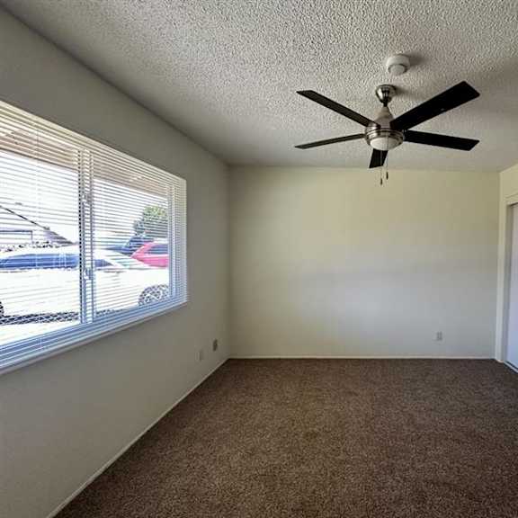 a room with a ceiling fan and carpeted floor.