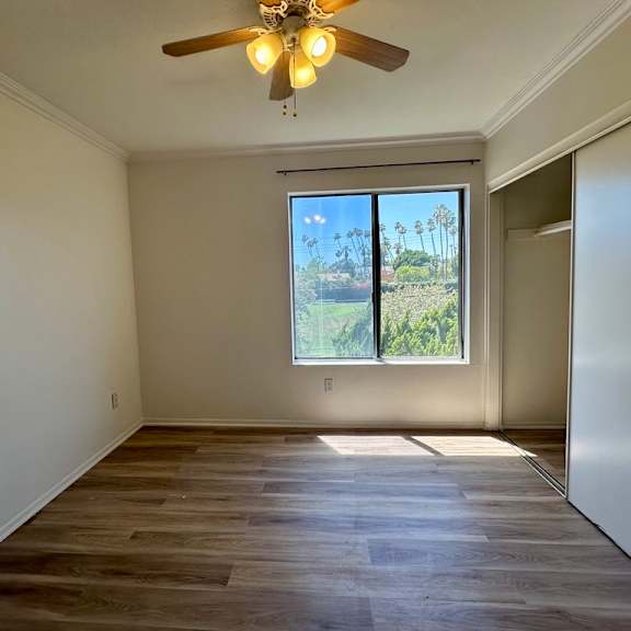 a room with a ceiling fan and a window overlooking a green landscape.