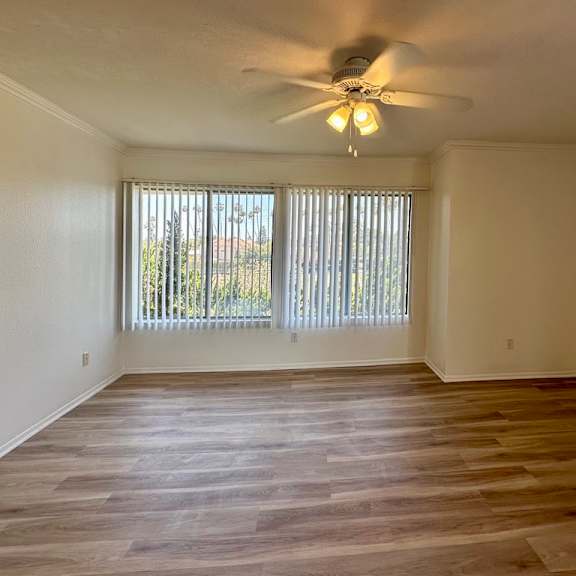 a room with a ceiling fan and wooden flooring.