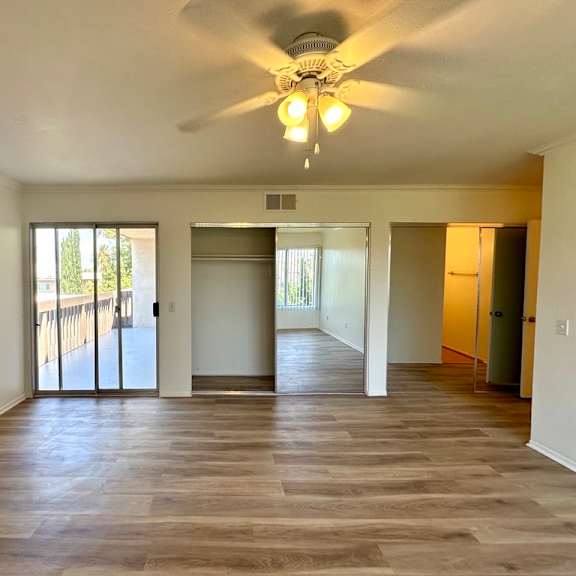 a spacious room with a ceiling fan and sliding glass doors.