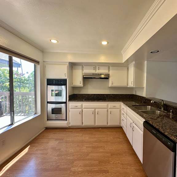 a kitchen with white cabinets and a black countertop.