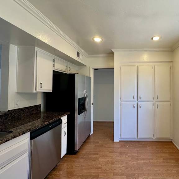 a kitchen with white cabinets and a black dishwasher.