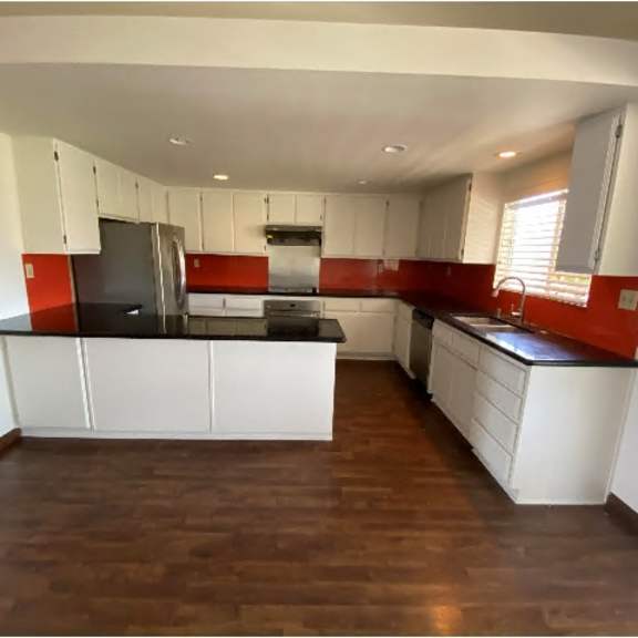 a kitchen with white cabinets and a black countertop.