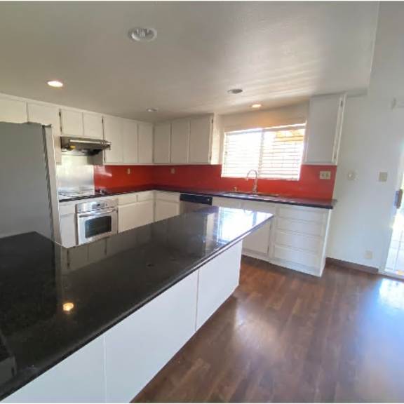 a kitchen with white cabinets and a black countertop.