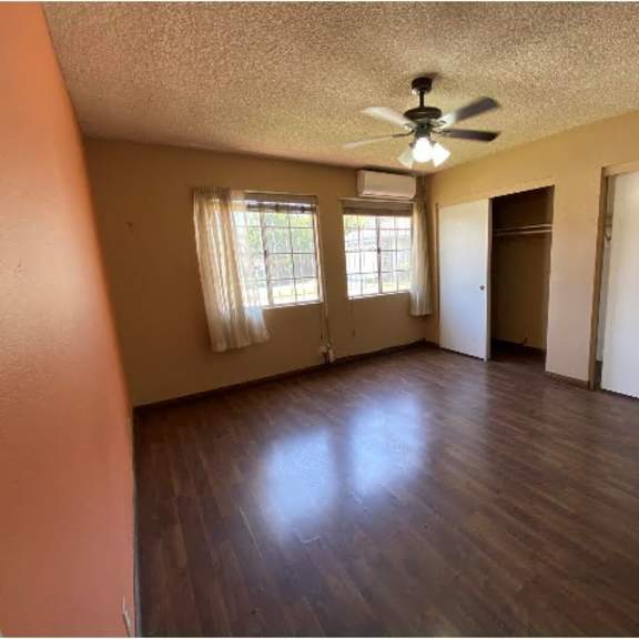 a room with a ceiling fan and wooden flooring.