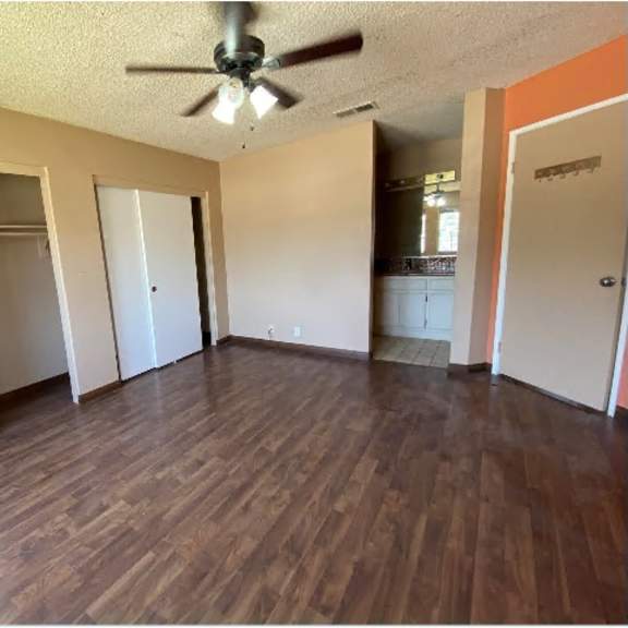 a room with a ceiling fan and wooden flooring.