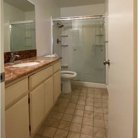 a bathroom with a toilet, sink, and shower.