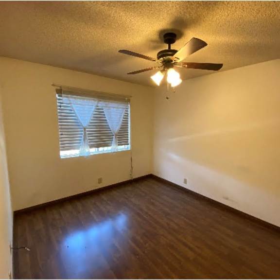a room with a ceiling fan and a window with blinds.