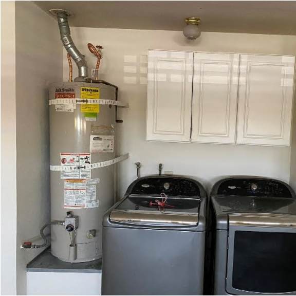 a small kitchen with a water heater and two ovens.