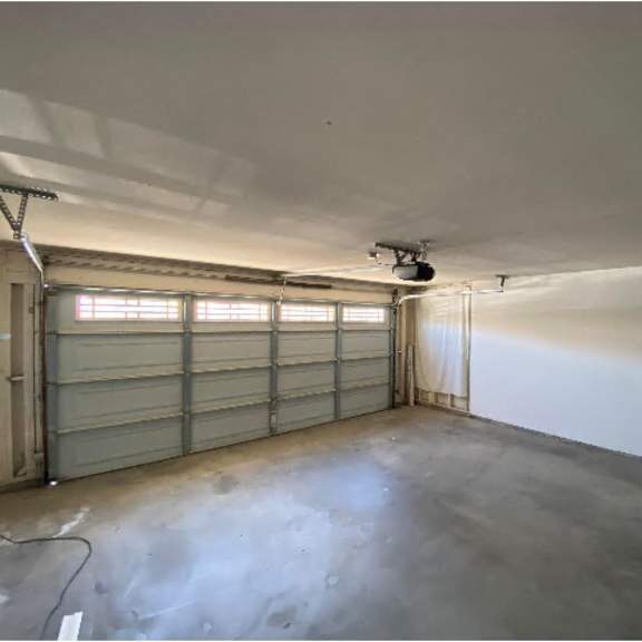 a garage with a concrete floor and a closed metal door.