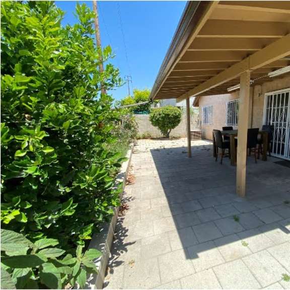 a patio area with a table and chairs under a roof.