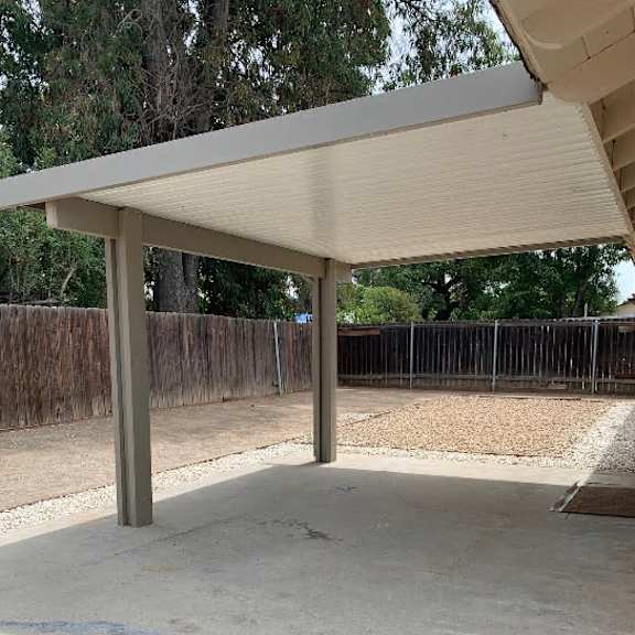 a concrete patio with a white pergola over it.