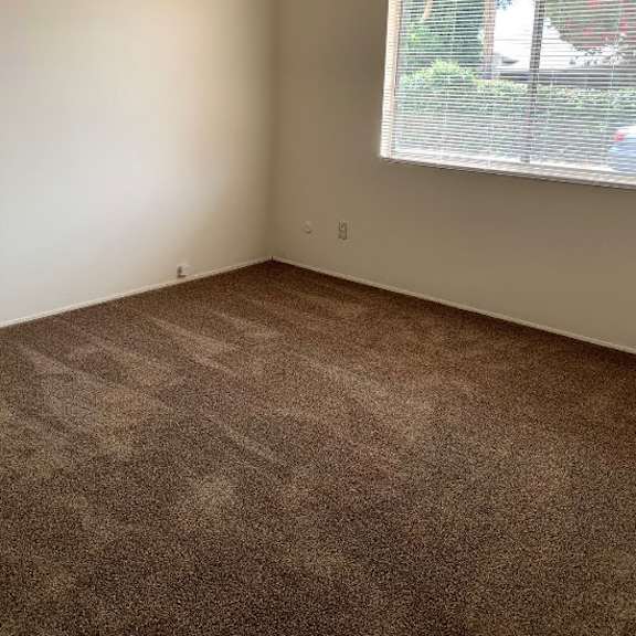 a room with a carpeted floor and a window with blinds.