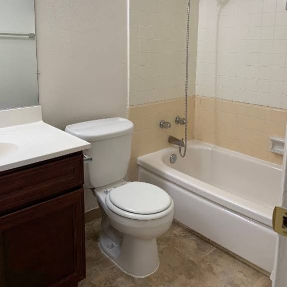 a white toilet sits next to a bathtub in a bathroom.