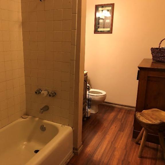 a bathroom with a tub, toilet and wooden floors.