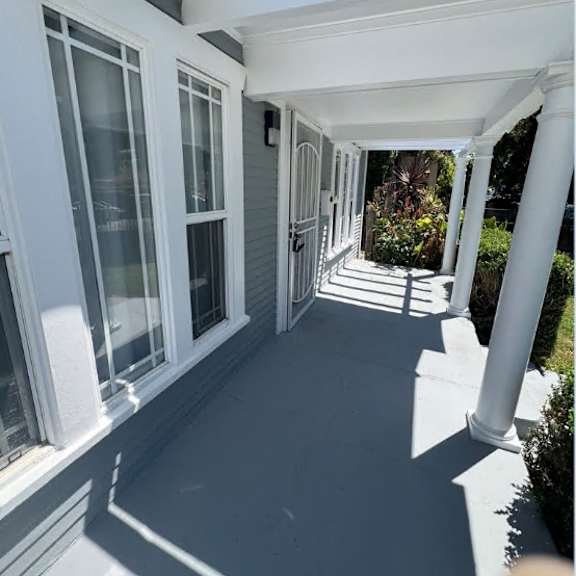 a white porch with a white railing and a white pillar.