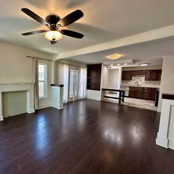 a spacious room with a fireplace and a ceiling fan.