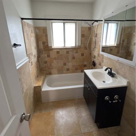 a bathroom with a tiled shower and a white sink.