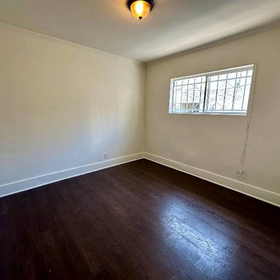 a room with a window and wooden flooring.