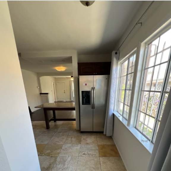 a kitchen with a refrigerator, sink, and cabinets.