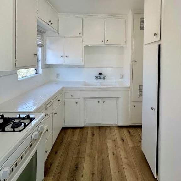 a kitchen with white cabinets and a wooden floor.