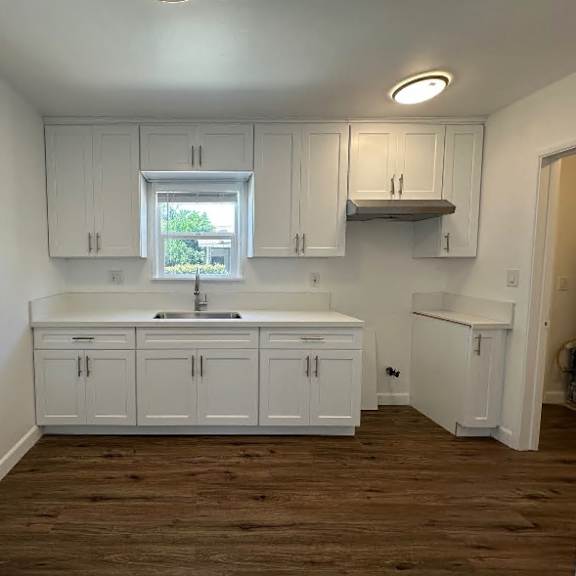 a kitchen with white cabinets and a window.