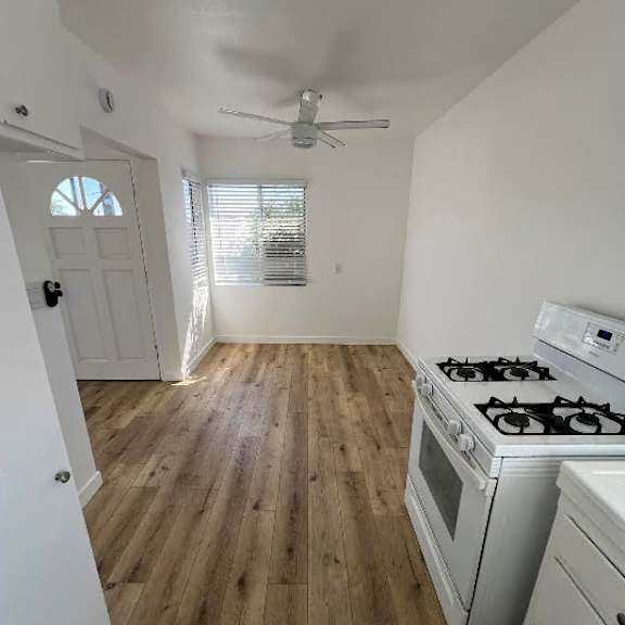 a kitchen with a white stove and wooden floors.